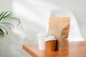 Three beverage containers and a paper bag on a wooden table